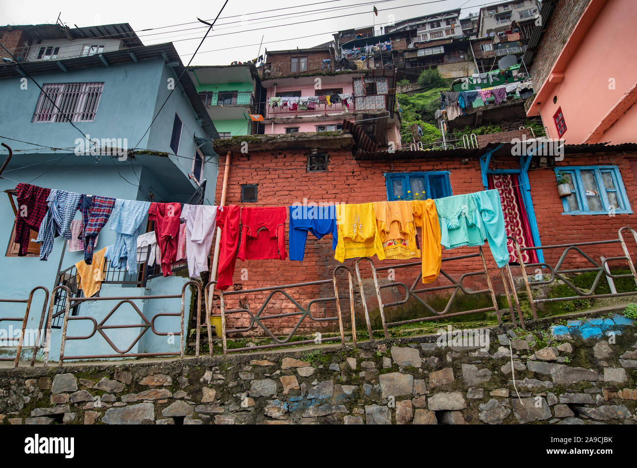 View of houses hugging the hillside in Shimla are constructed close to each other. In the foreground clothes are being dried Stock Photo
