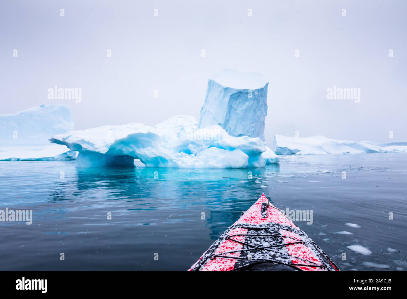 Kayaking between icebergs on a red kayak in Antarctica, POV (point of view) photo with frozen white landscape and blue ice, amazing scene in Antarctic Stock Photo