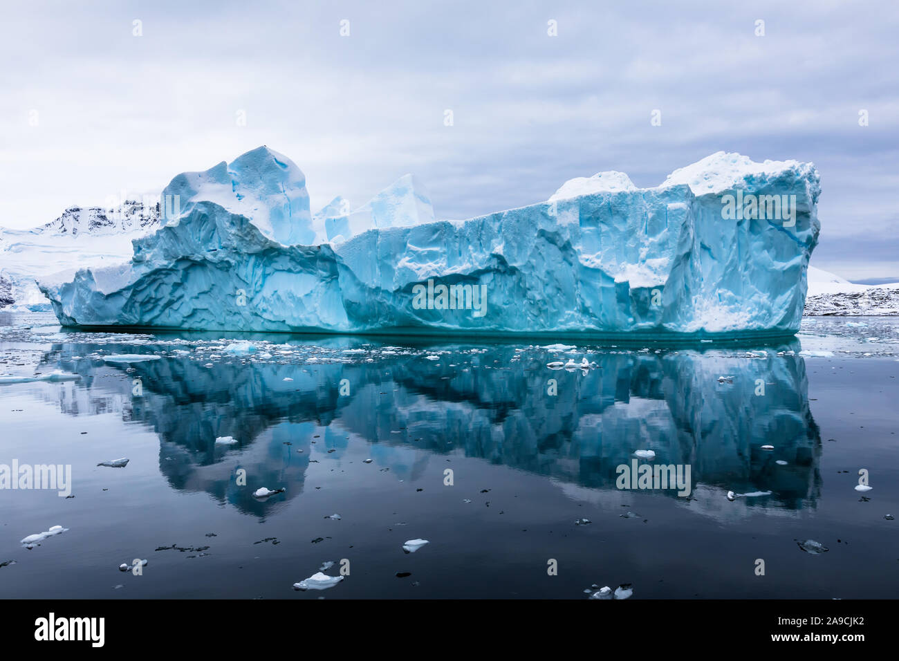Impressive iceberg with blue ice and beautiful reflection on water in Antarctica, scenic landscape in Antarctic Peninsula Stock Photo