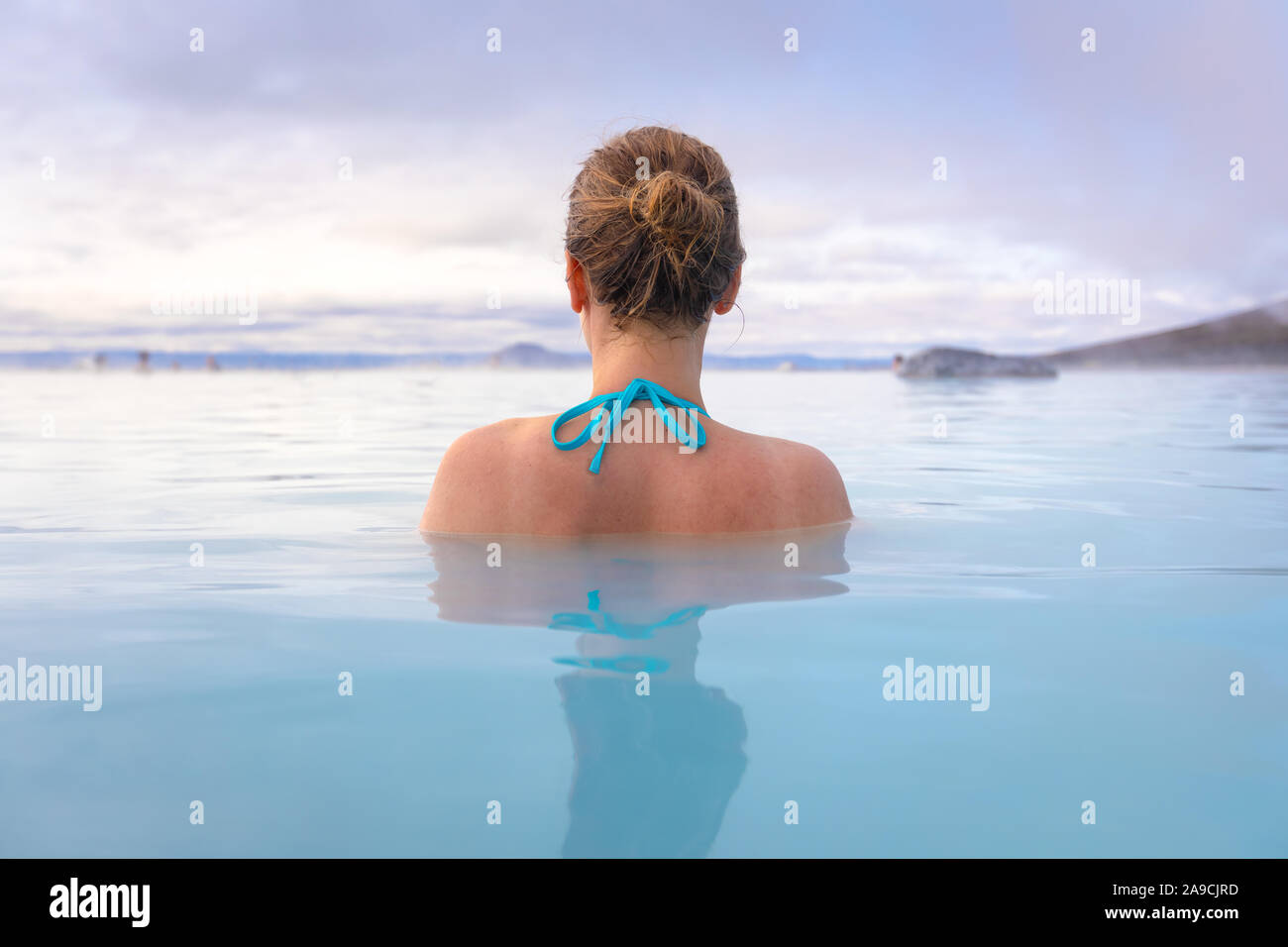 Geothermal spa in Iceland with young woman enjoying bathing in hot thermal pool with hotspring water for wellness and skin treatment, icelandic experi Stock Photo