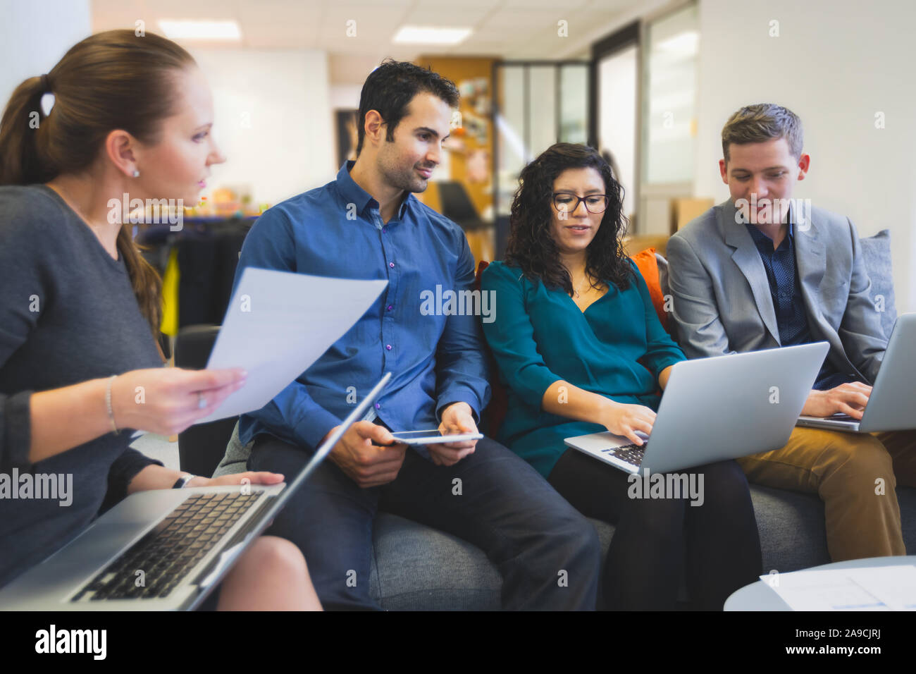 Group of people in office working and discussing together with computers, project team meeting about strategy, coworkers helping each other with creat Stock Photo