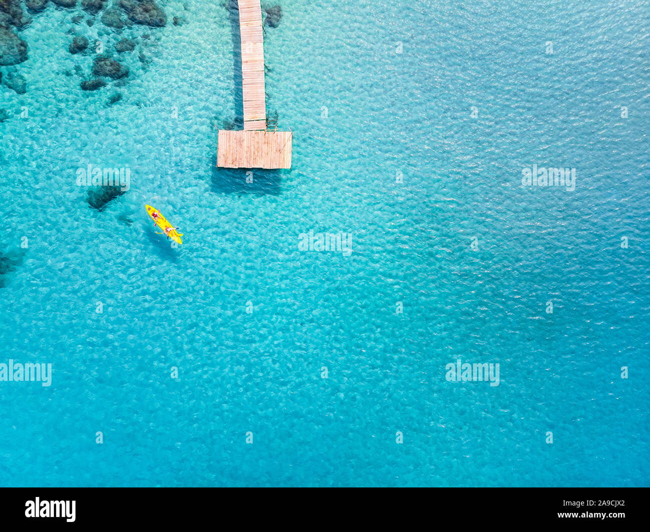 Tropical beach viewed from drone at beautiful vacation holidays destination with transparent turquoise sea water, pier and people kayaking. Top down a Stock Photo