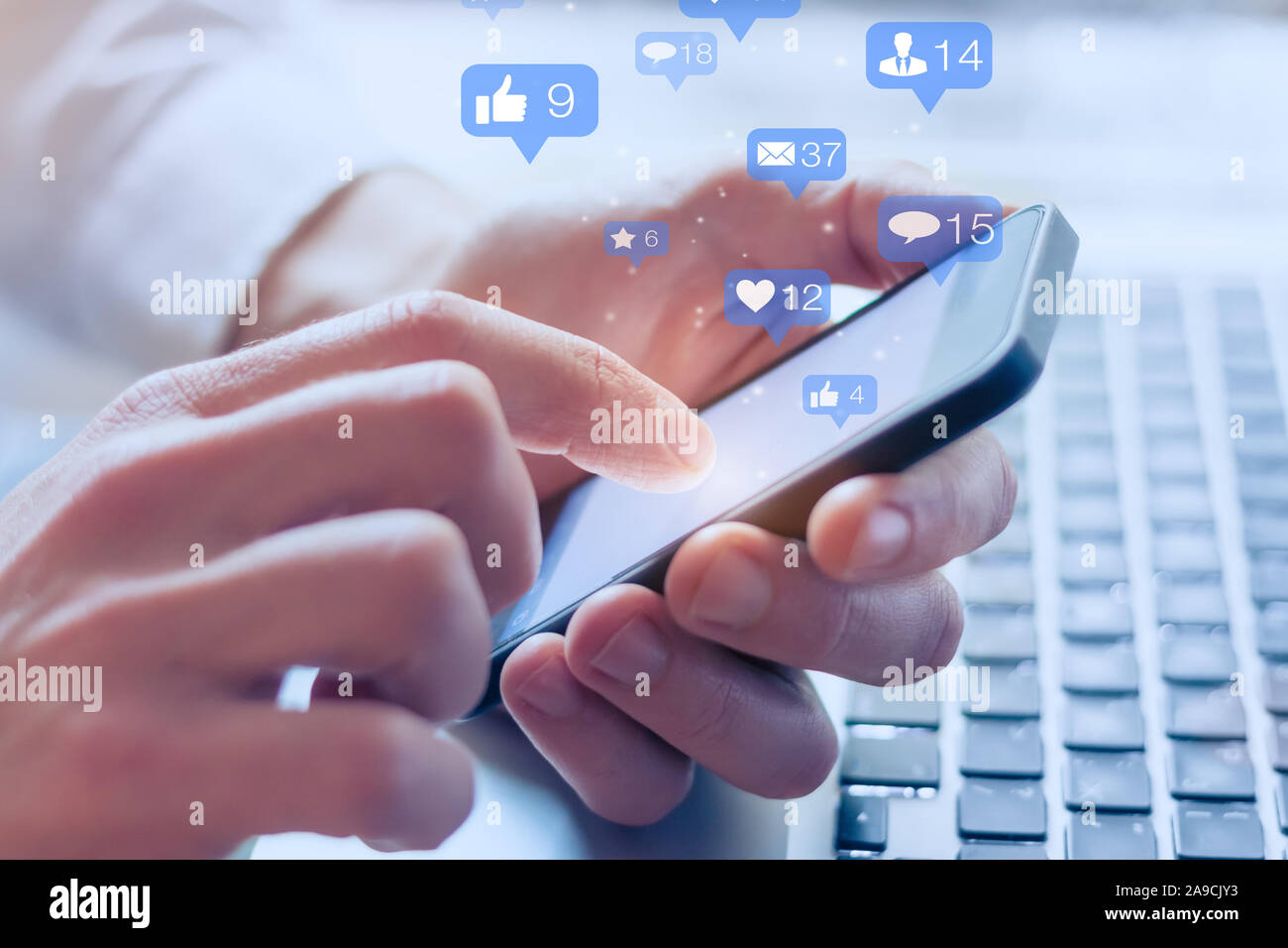 Social media interactions on mobile phone, concept with notification icons of like, message, email, comment and star above smartphone screen, person h Stock Photo