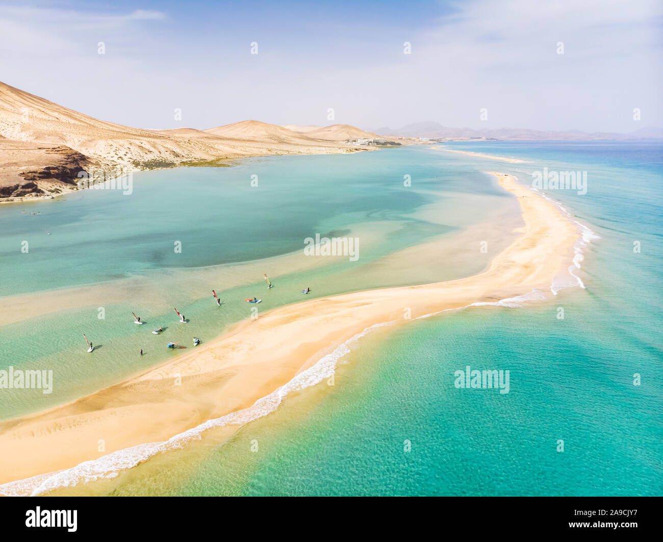 Aerial view of beach in Fuerteventura island with windsurfers learning windsurfing in blue turquoise water during summer vacation holidays, Canary isl Stock Photo