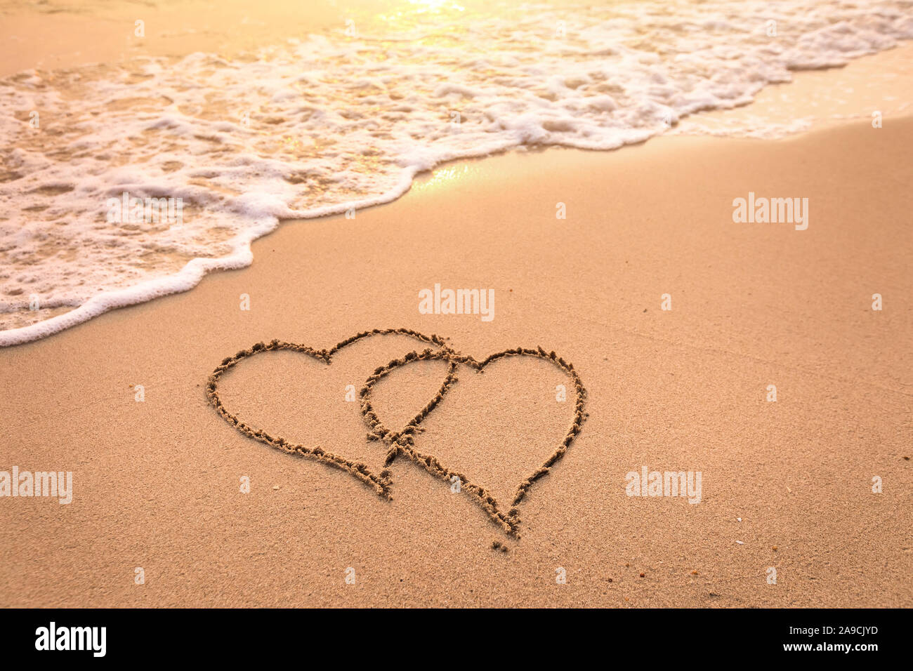 Romantic honeymoon holiday or Valentine's day on the beach concept with two hearts drawn on the sand, tropical getaway for couples, love symbol Stock Photo