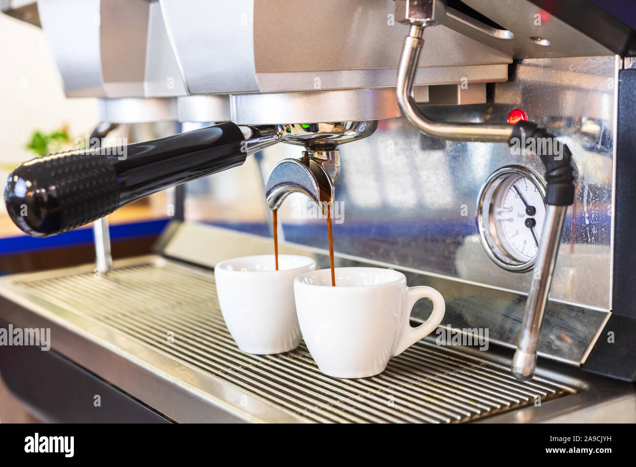 Espresso coffee machine brewing two shots in white cups, professional Italian equipment at restaurant or bar counter, close-up Stock Photo