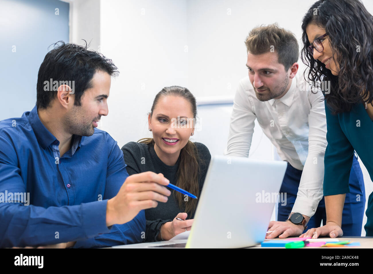 Group of business people discussing ideas and strategy in meeting room, smiling woman, multiple ethnicity, leadership, computer on office table Stock Photo