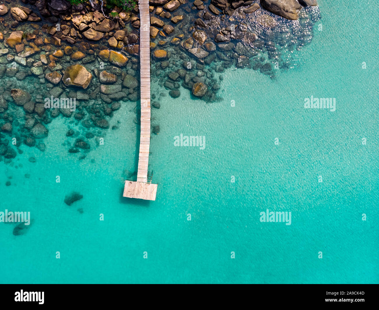 Island aerial view from drone, beach holiday vacation destination, transparent turquoise sea water with wooden pier and rocks, beautiful tropical para Stock Photo