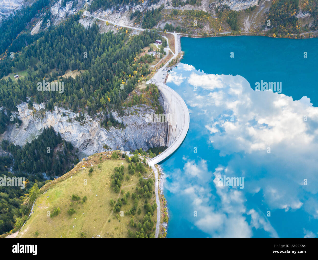 Water dam and reservoir lake in Swiss Alps to produce hydropower, hydroelectricity generation, renewable energy, aerial drone photography Stock Photo
