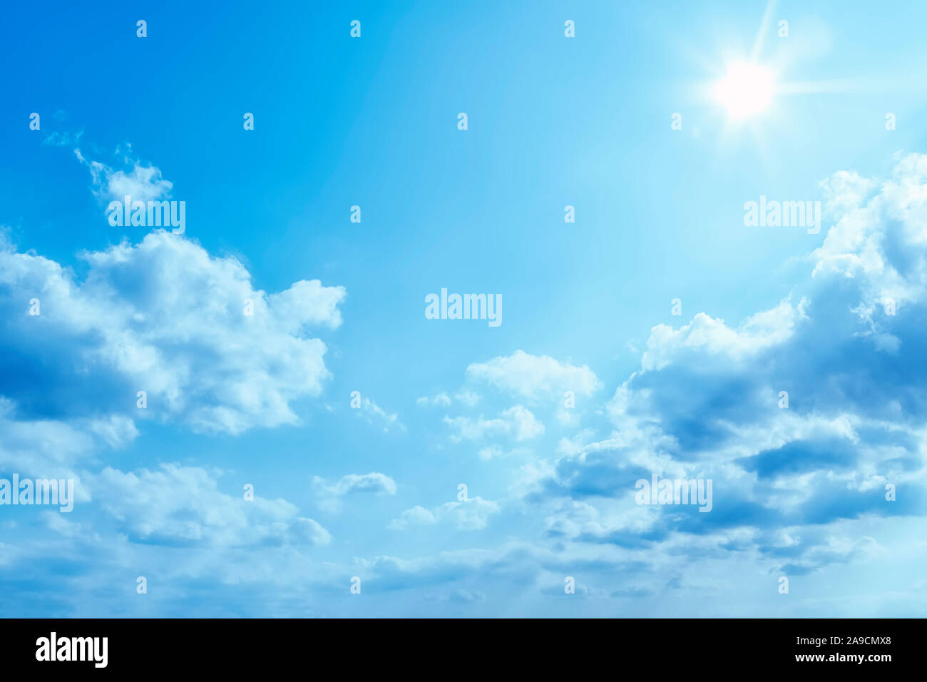 a bright blue sky with sun and clouds background Stock Photo - Alamy