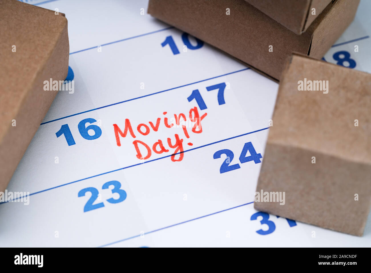 Elevated View Of Moving Day Text On Calendar With Small Cardboard Boxes Stock Photo
