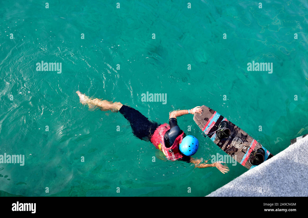 Wakeboarder swimming into pier with his board before next tow on cable system, Uvala valovine bay, Croatia Stock Photo