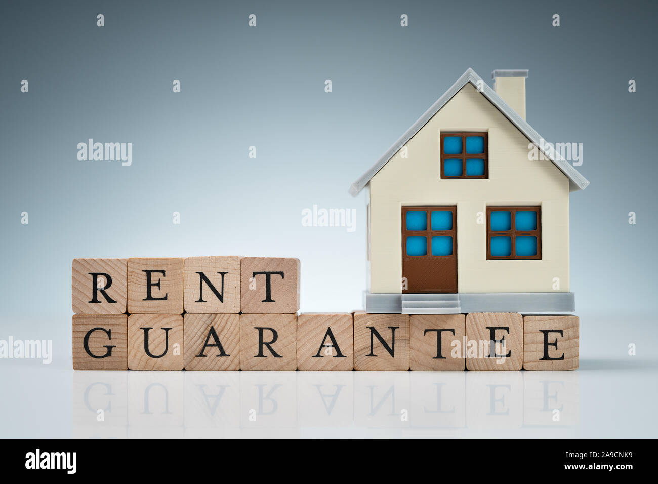 Close-up Of Small House Model On Wooden Blocks With Rent Guarantee Text Over Table Stock Photo