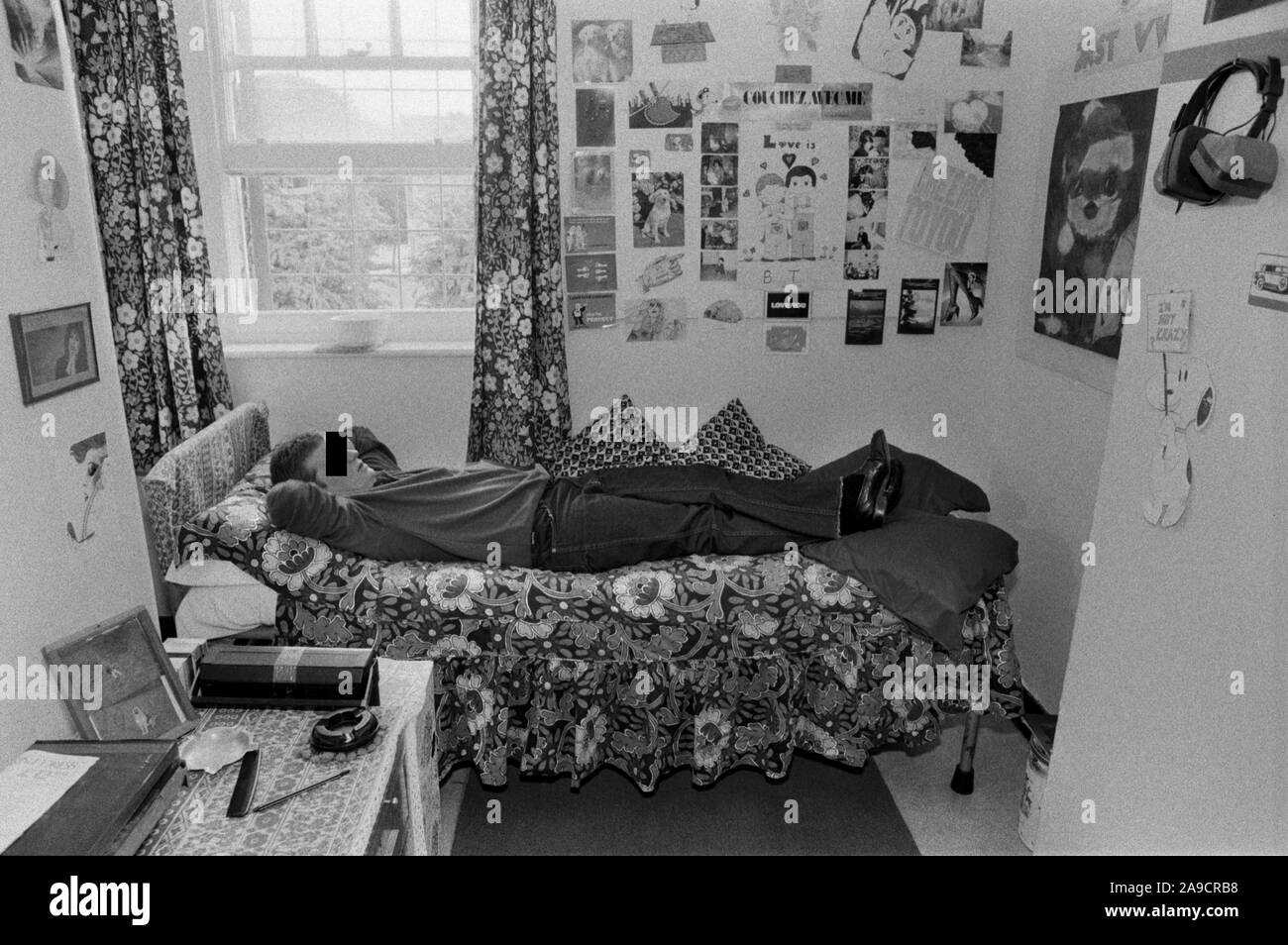 Woman in prison cell UK 1980s. Female inmate prisoner lying on bed with her possessions, photographs and drawing stuck to the wall of her cell as decoration. HM Prison Styal Wilmslow Cheshire England 1986 HOMER SYKES Stock Photo