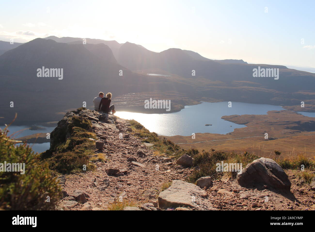 Young couple sitting on the saddle of the Mountain Stac Pollaidh in the Scottish Highlands Stock Photo