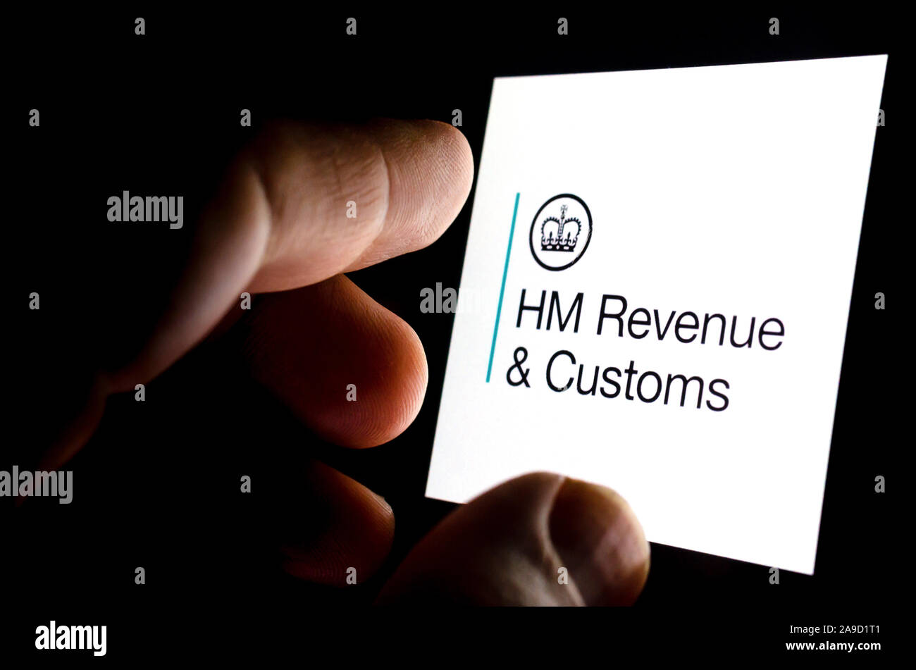 HMRC app logo on a glowing smartphone screen and the finger touching it. Conceptual photo for citizen's interaction and contact with HMRC. Stock Photo