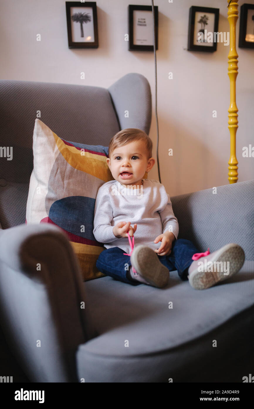Cute baby girl sitting on big armchair and smile Stock Photo