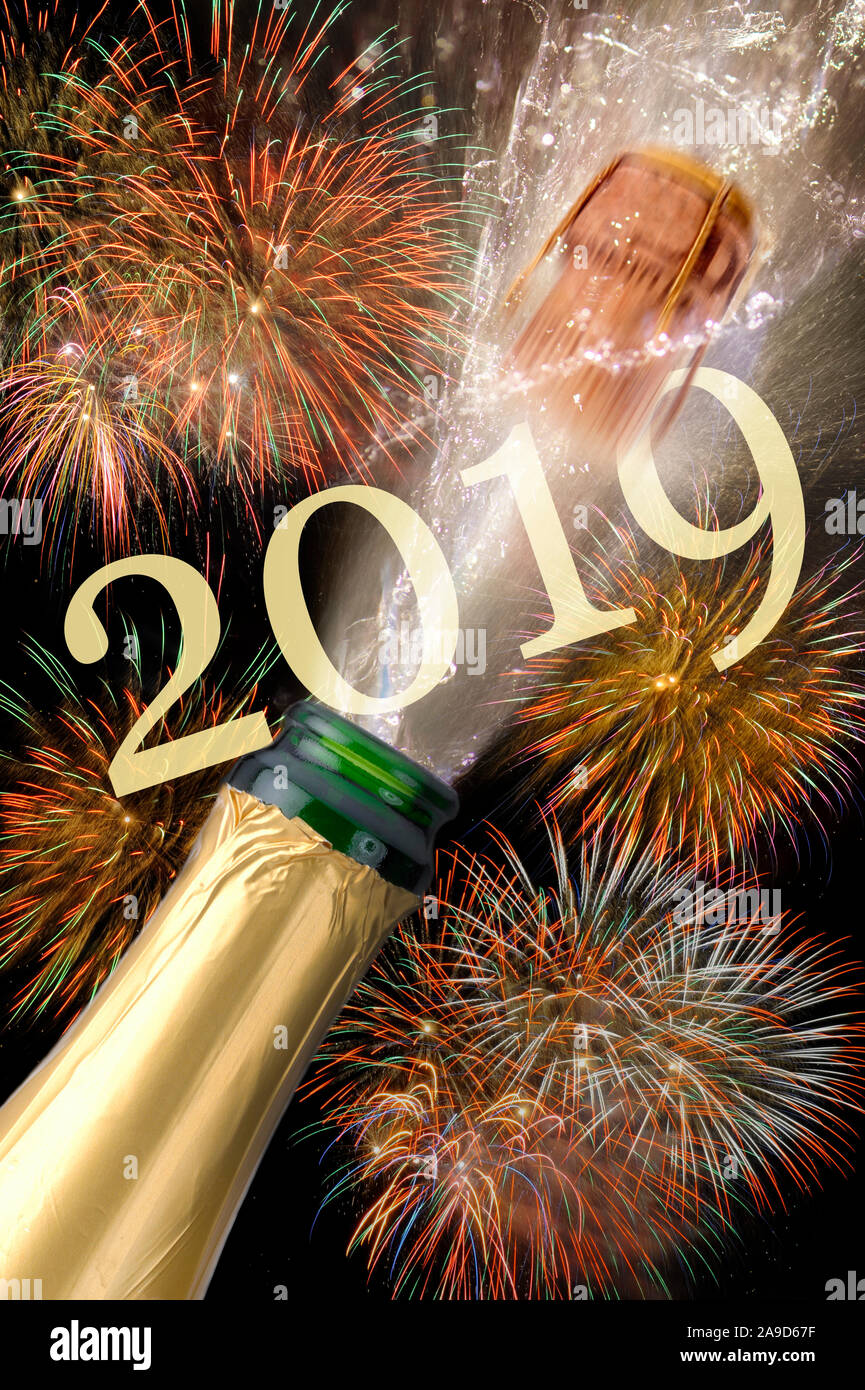 Champagne bottle with popping cork, brilliant fireworks in the background, New Year 2019 Stock Photo