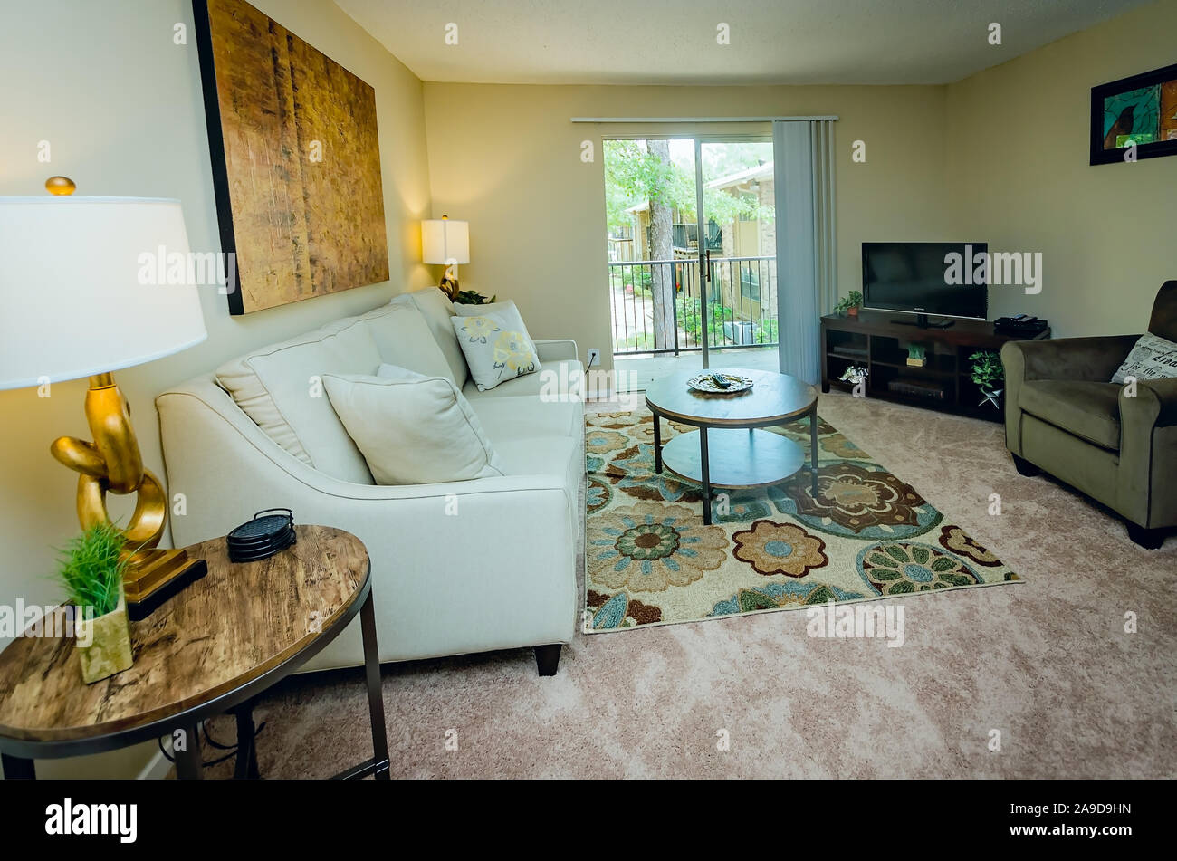 An apartment living room features a sliding glass door leading to the balcony at Autumn Woods apartment homes in Mobile, Alabama. Stock Photo