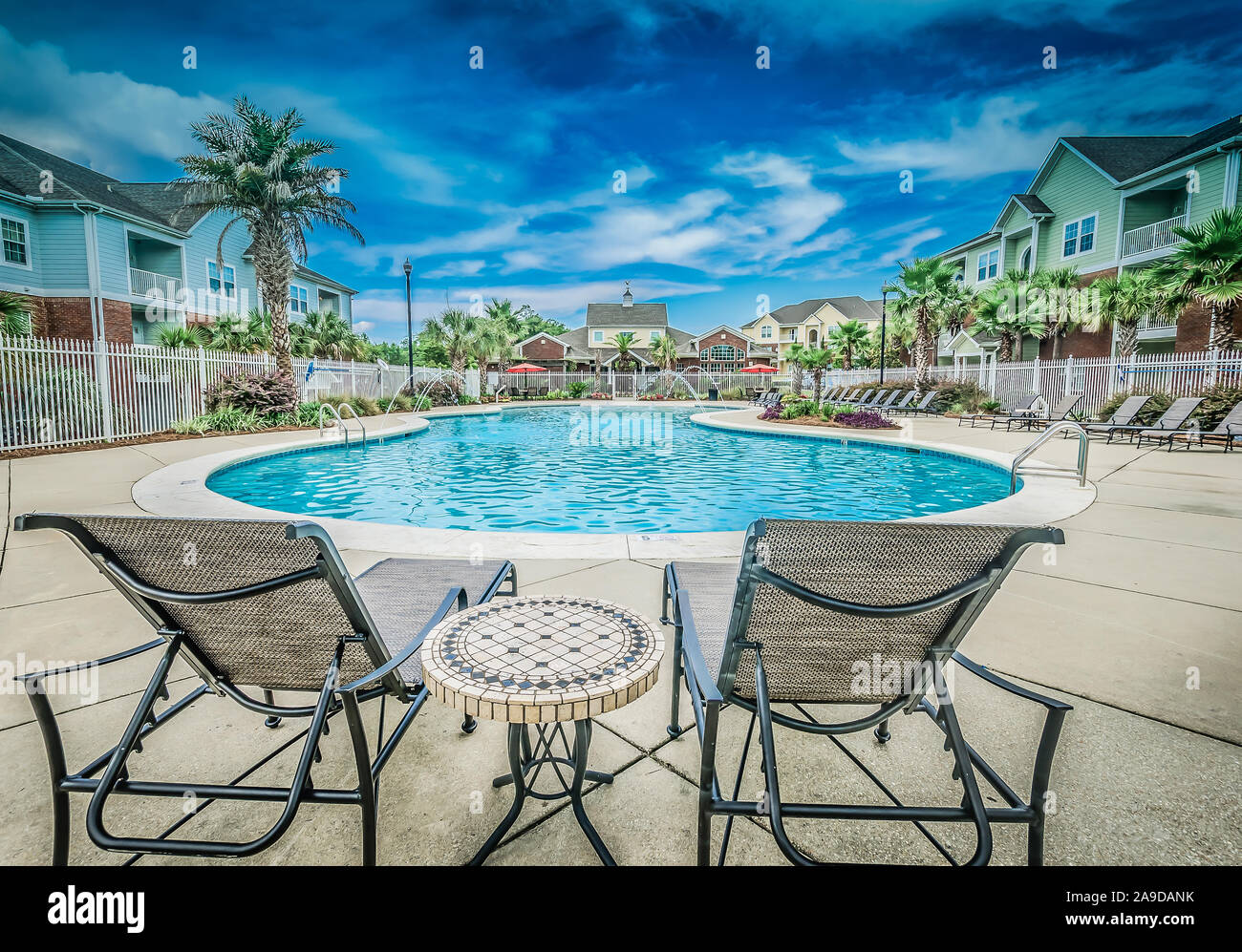 Lounge chairs overlook the swimming pool at Cypress Cove Apartment Homes in Mobile, Alabama. The apartment complex is owned and operated by Sealy. Stock Photo