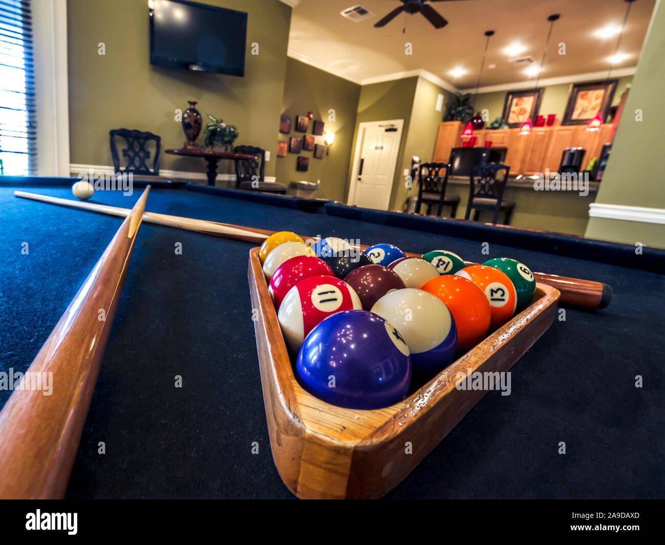 Billiard balls are racked on a pool table alongside two pool cues in the clubhouse at Cypress Cove Apartment Homes in Mobile, Alabama. Stock Photo