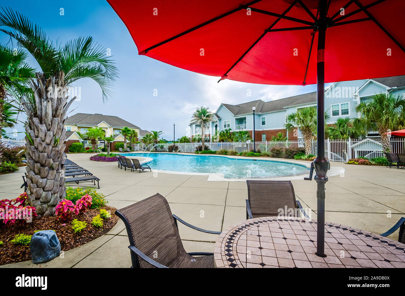 A patio umbrella shades a table by the builtin swimming pool at