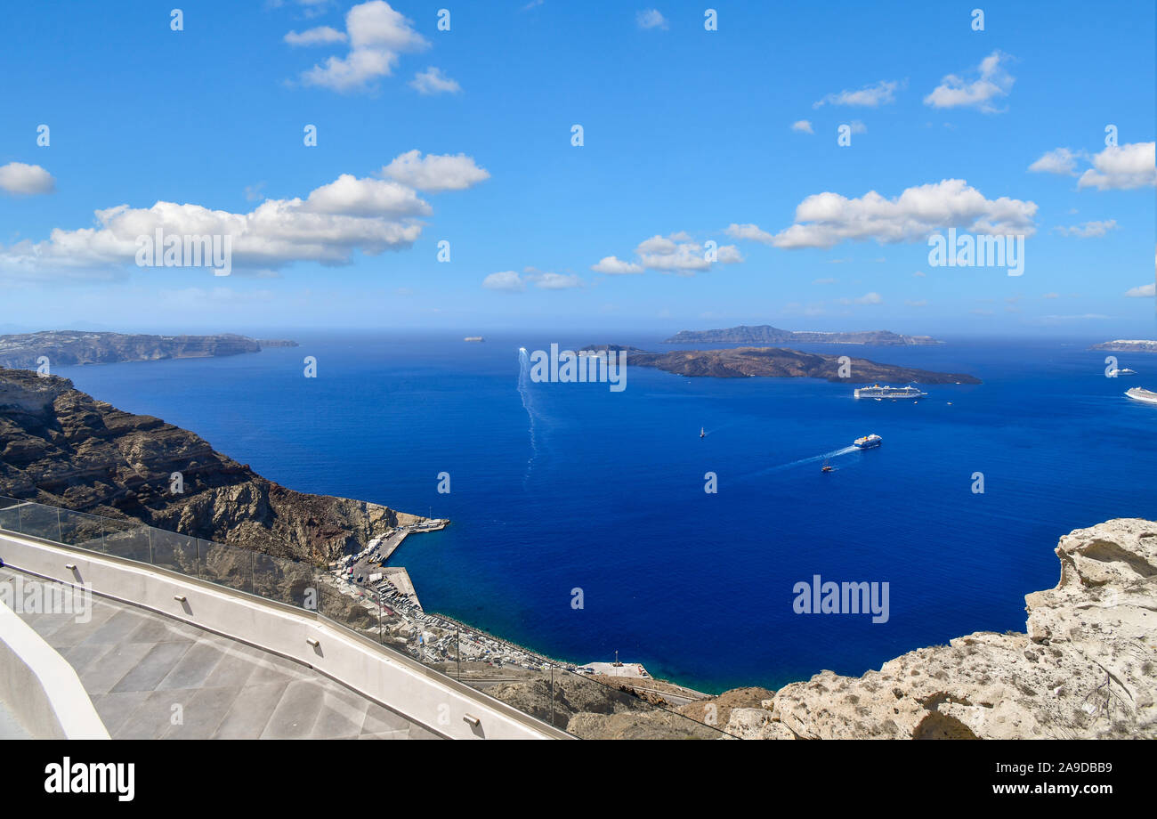 Ships cruise through the center of the Caldera past small islands on the Aegean Sea in front of the port of Santorini Greece Stock Photo