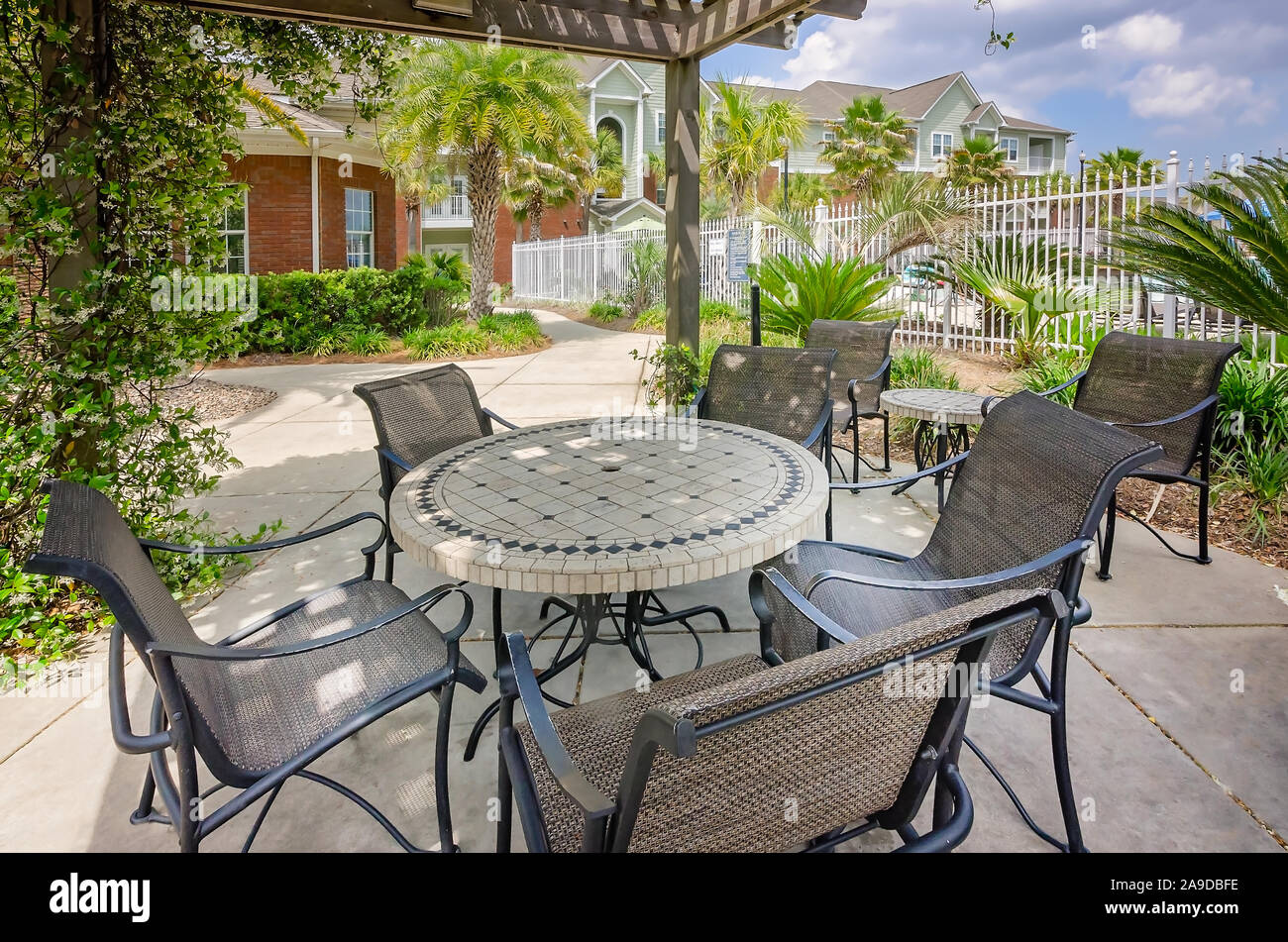 Patio tables and chairs are situated beneath a vine-covered pergola at Cypress Cove Apartment Homes in Mobile, Alabama. Stock Photo