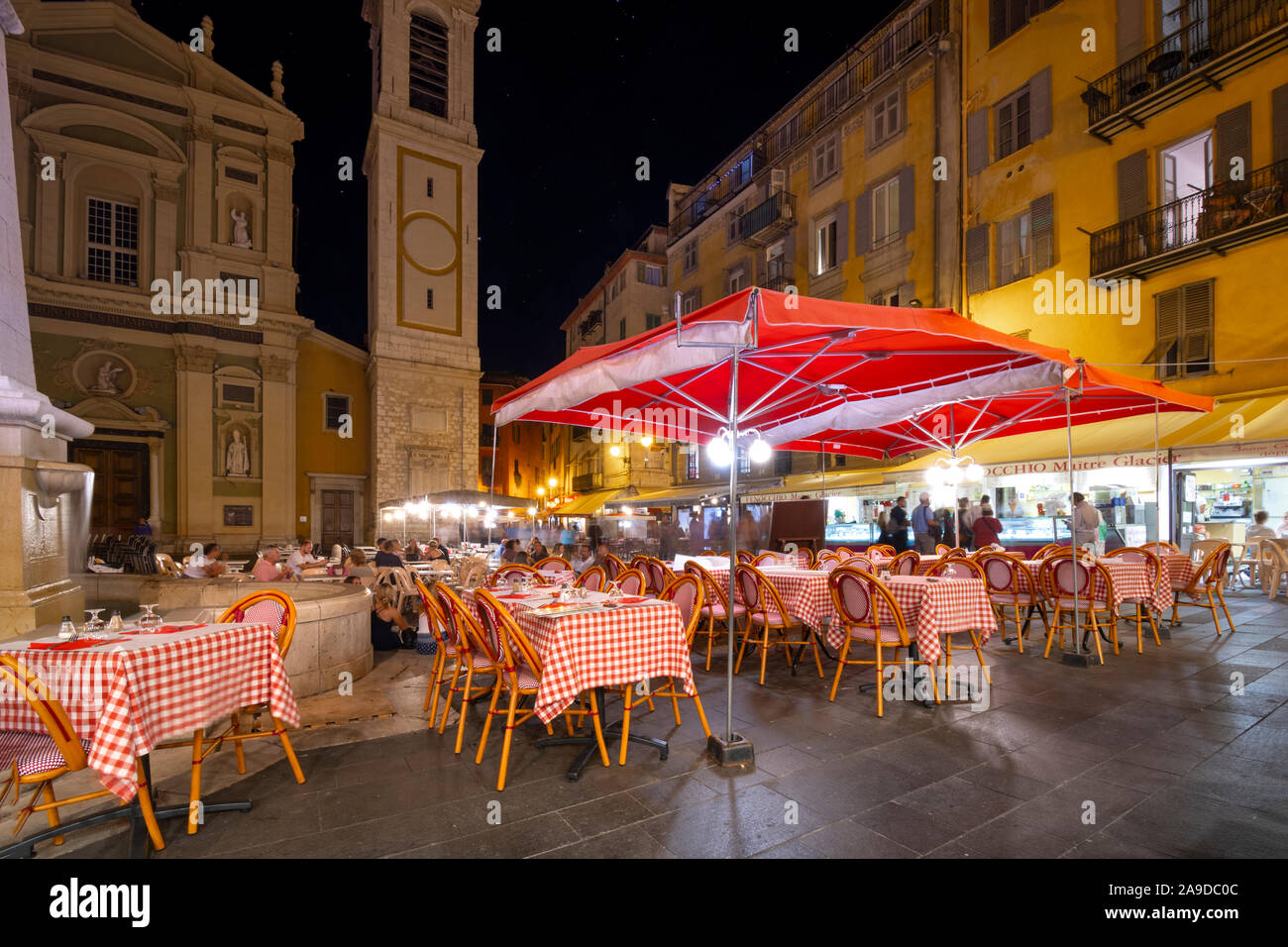 Tourists enjoy a late night at a sidewalk cafe and gelateria in the picturesque Place Rossetti square in Old Town Vieux Nice, France. Stock Photo