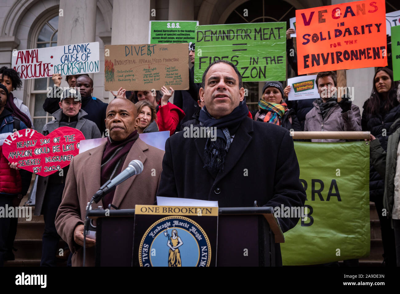 New York, USA. 14th Nov, 2019. (L-R) Brooklyn Borough President Eric Adams and New York City Council Member Costa Constantinides announce a resolution calling for ban on business with companies tied to the Amazon Wildfires on the steps of New York City Hall on November 14, 2019. An annual 5% increased demand for beef has prompted South American ranchers to burn swaths of the historic rainforest, an asset in the fight against climate change, which have gone out of control. (Photo by Gabriele Holtermann-Gorden/Pacific Press) Credit: Pacific Press Agency/Alamy Live News Stock Photo