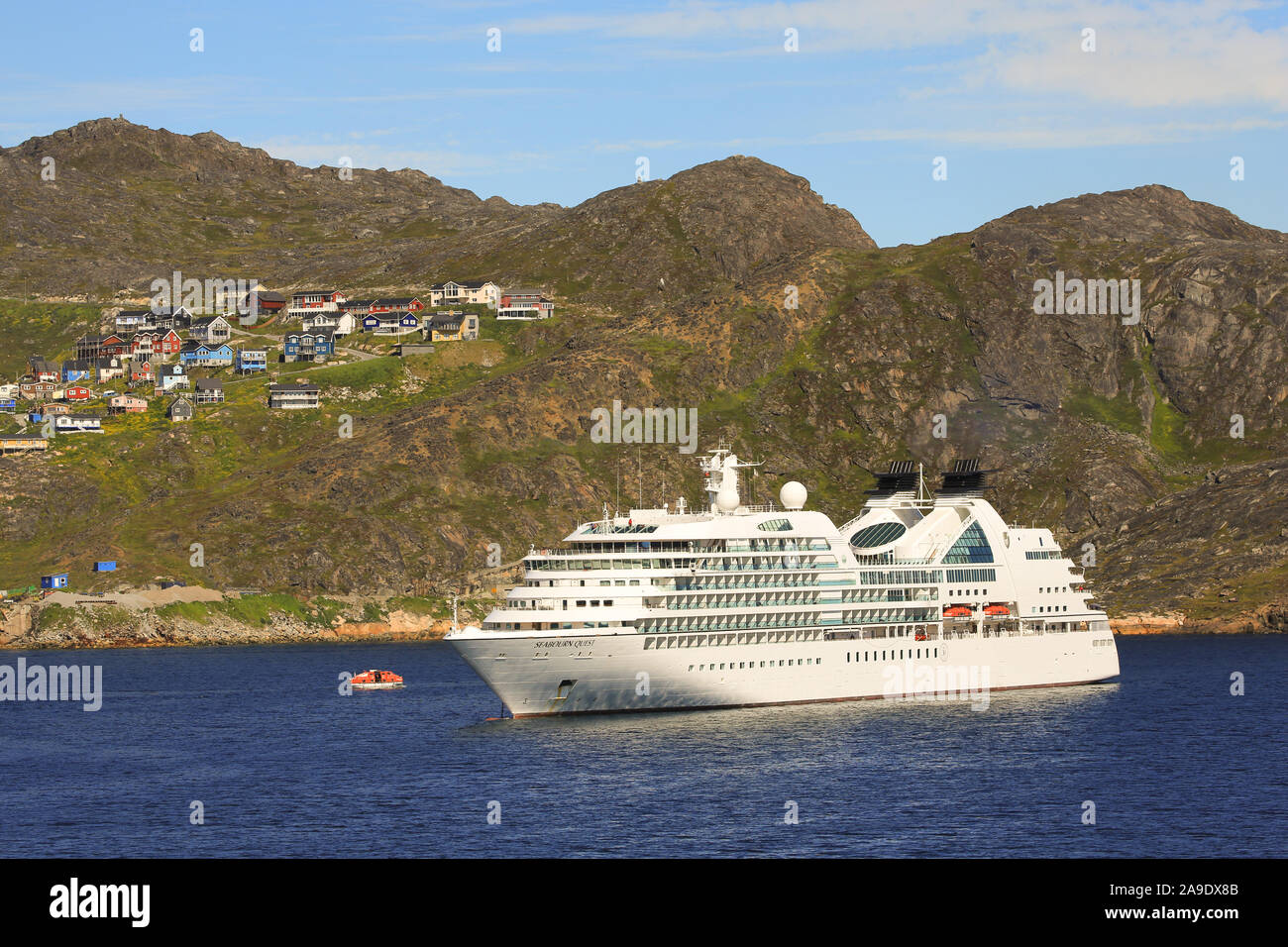 The cruise ship Seabourn Quest anchored off the town of Qaqortoq on the west coast of Greenland. Tendering to shore is underway. Stock Photo