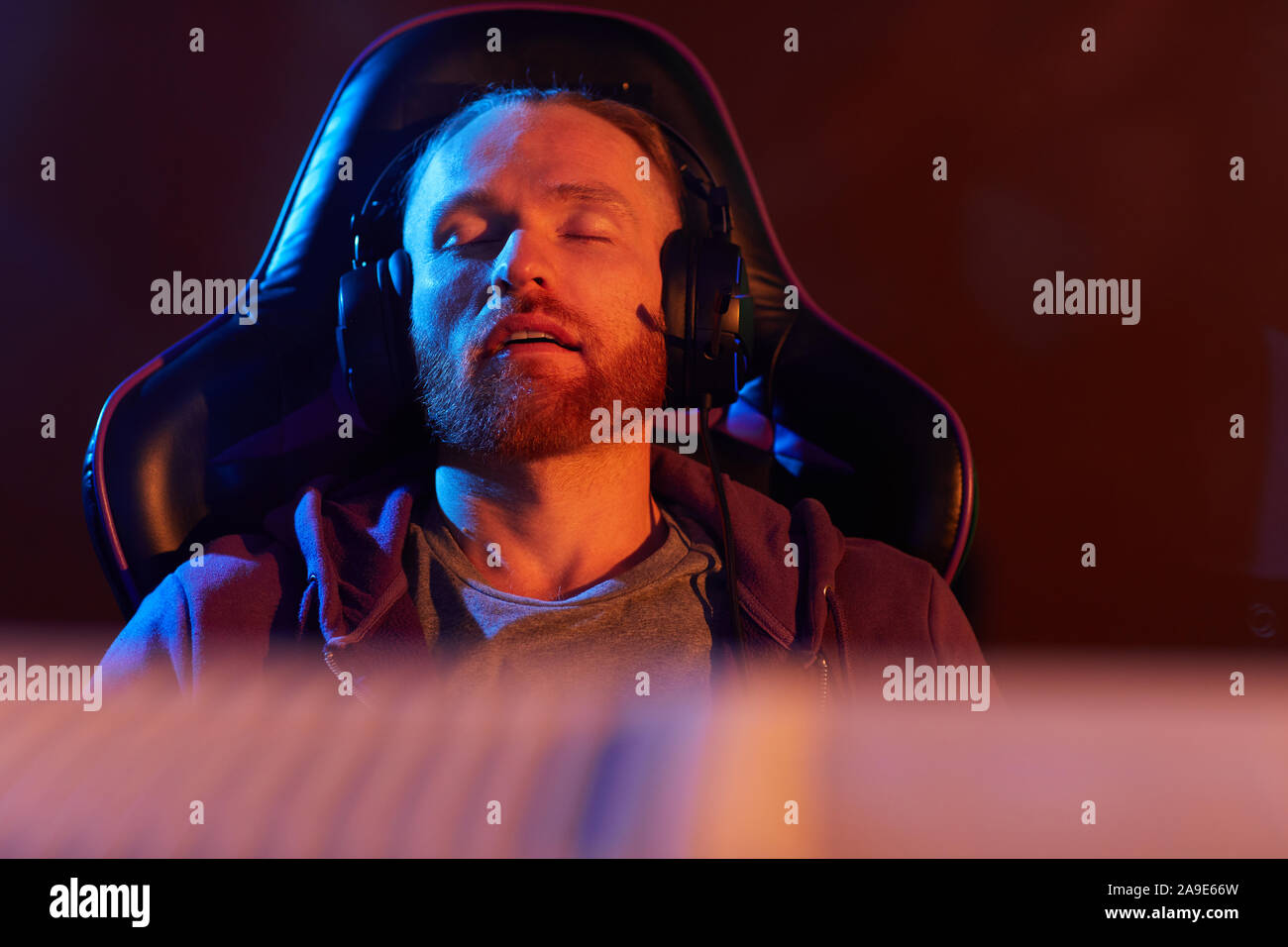 Young bearded man in headphones sitting in gaming chair and sleeping he