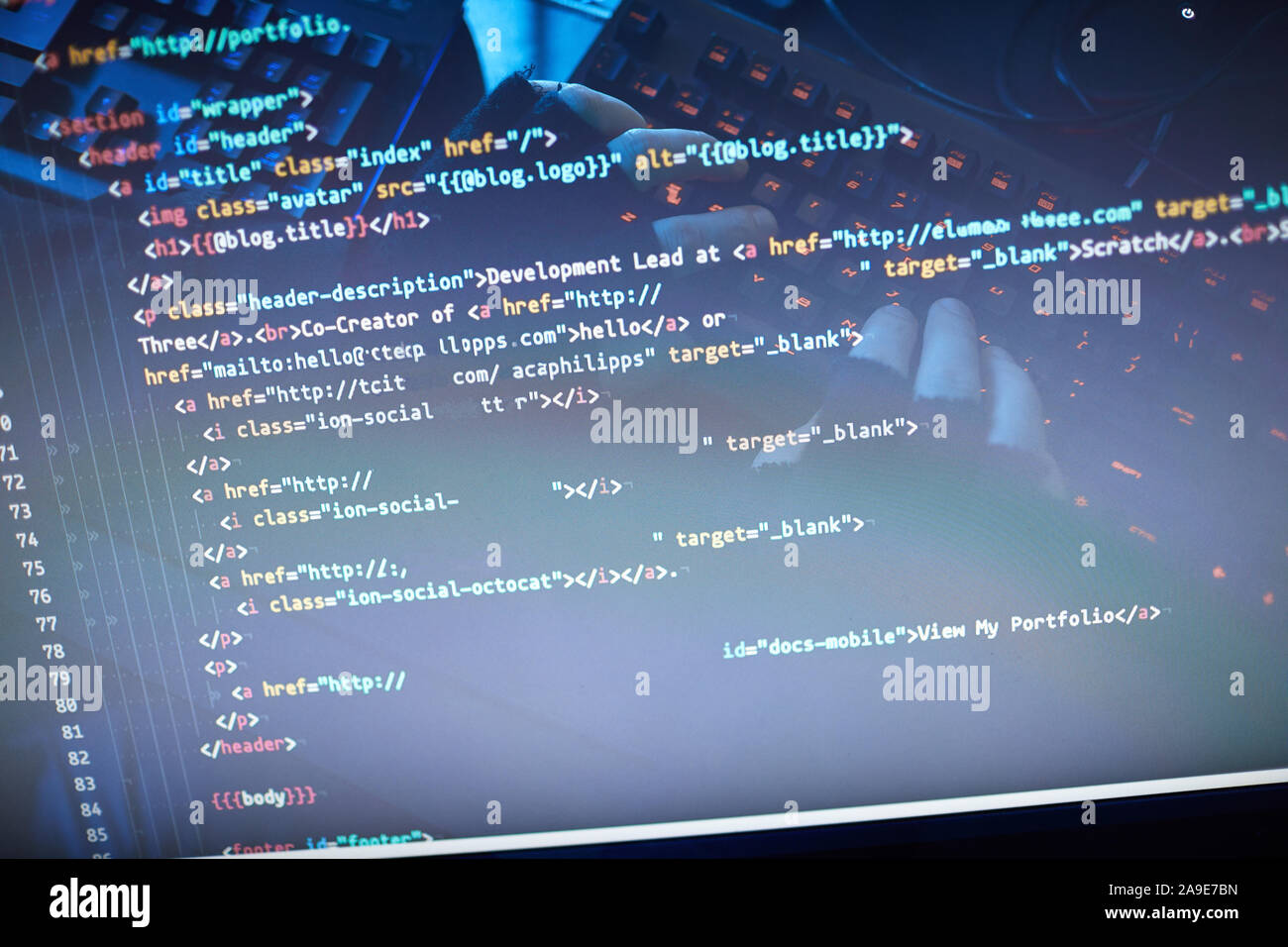 Close-up of man typing computer codes and reading them on computer monitor Stock Photo