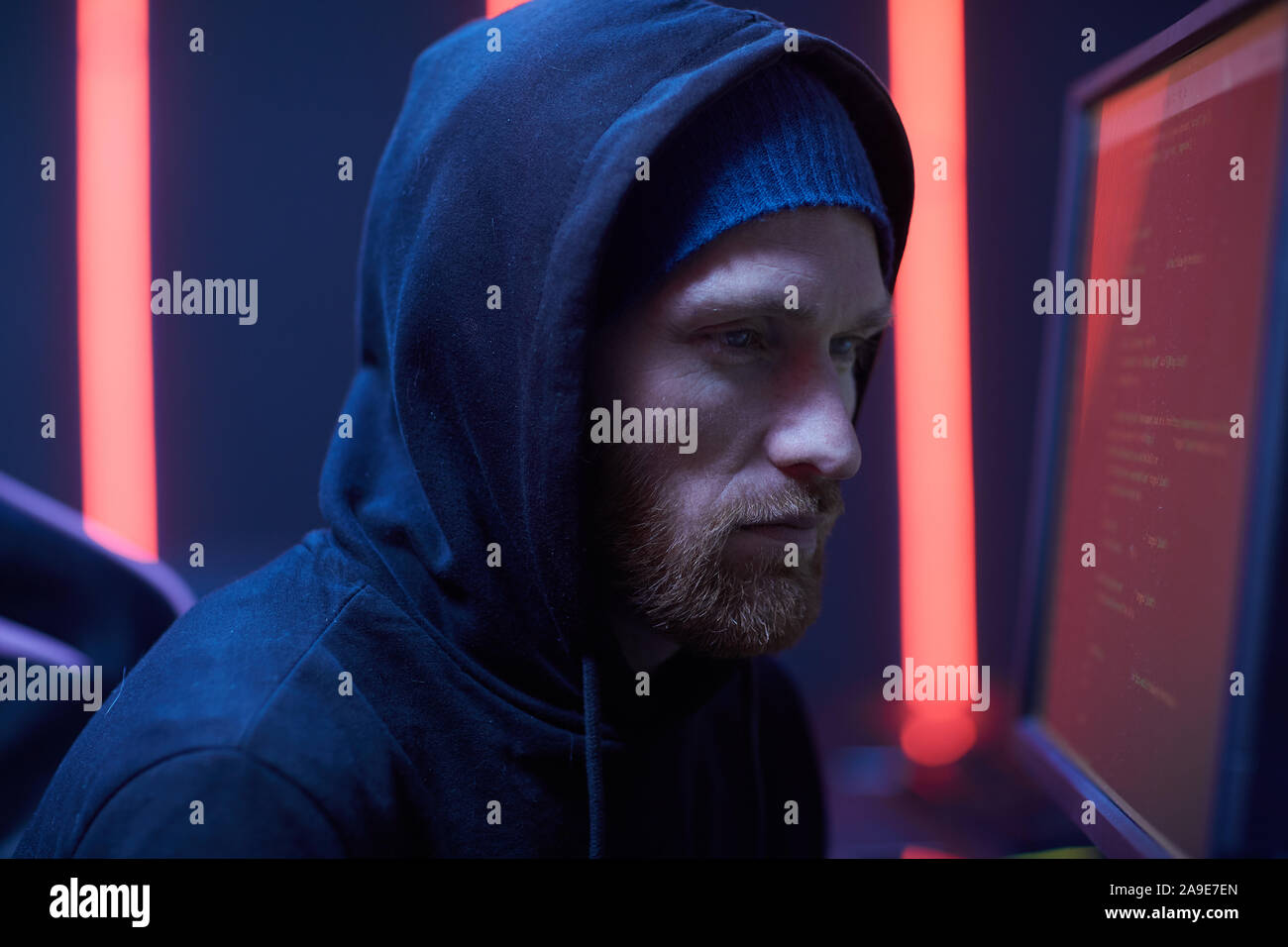 Serious computer programmer wearing black hoody concentrating on his ...