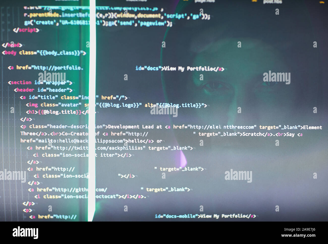 Close-up of computer monitor with codes and symbols and computer hacker reflecting on the monitor Stock Photo