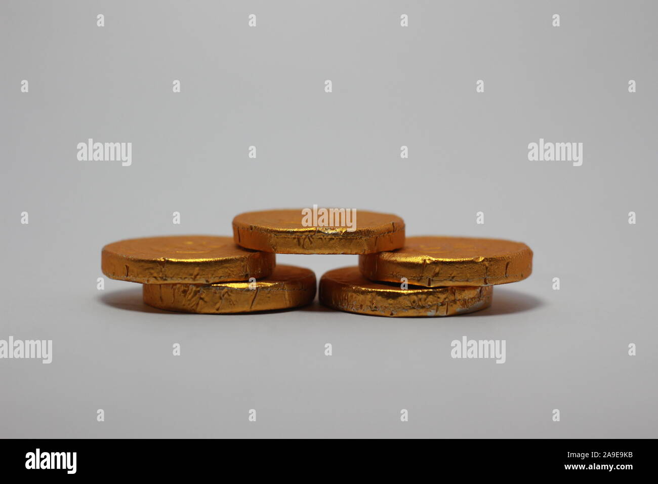 chocolate shaped like coins in gold foil sheet isolated on white background Stock Photo