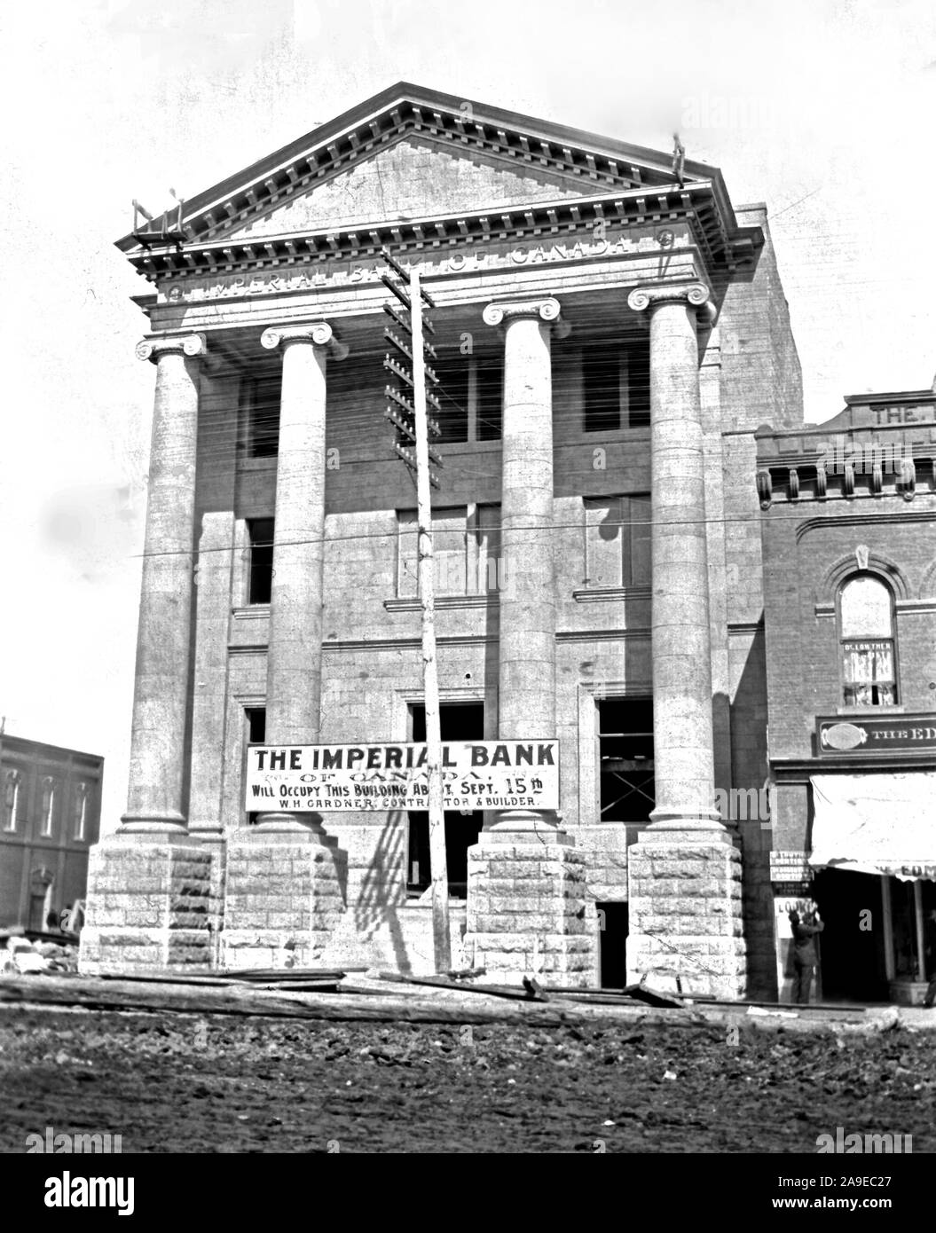 A banner across the front of the building declares that 'The Imperial Bank of Canada will occupy this building about Sept 15th, W. H. Gardner, Contractor and Builder.'. Stock Photo
