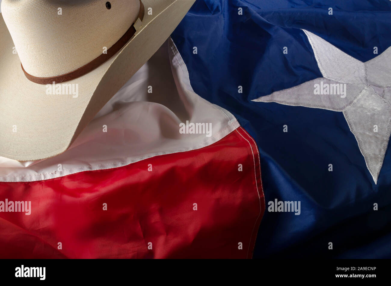 Cowboy hat and boots represent a way of life in the great state of Texas by resting on the Lone star state flag. Stock Photo