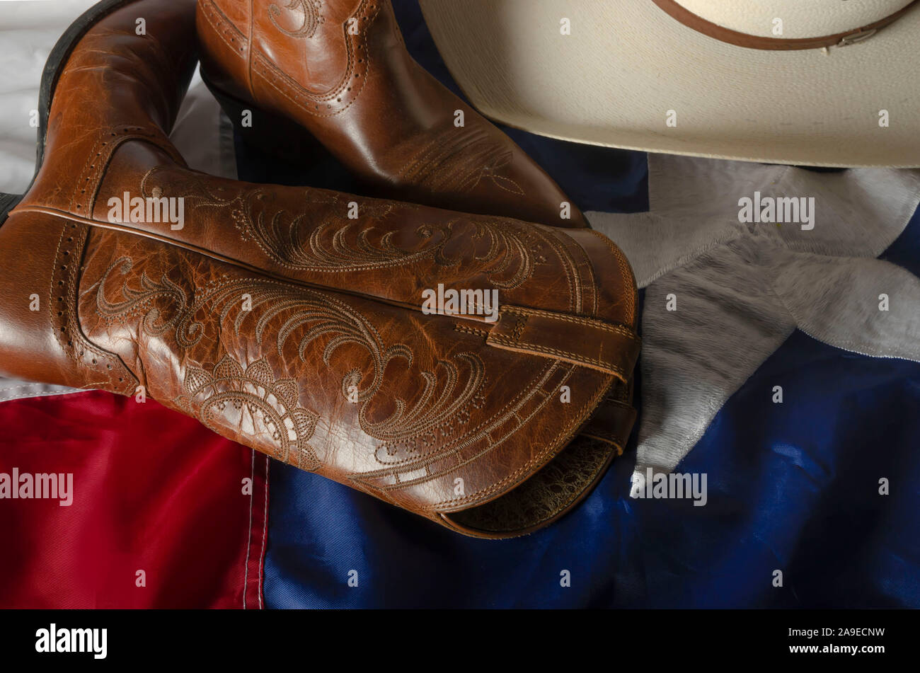 Cowboy hat and boots represent a way of life in the great state of Texas by resting on the Lone star state flag. Stock Photo