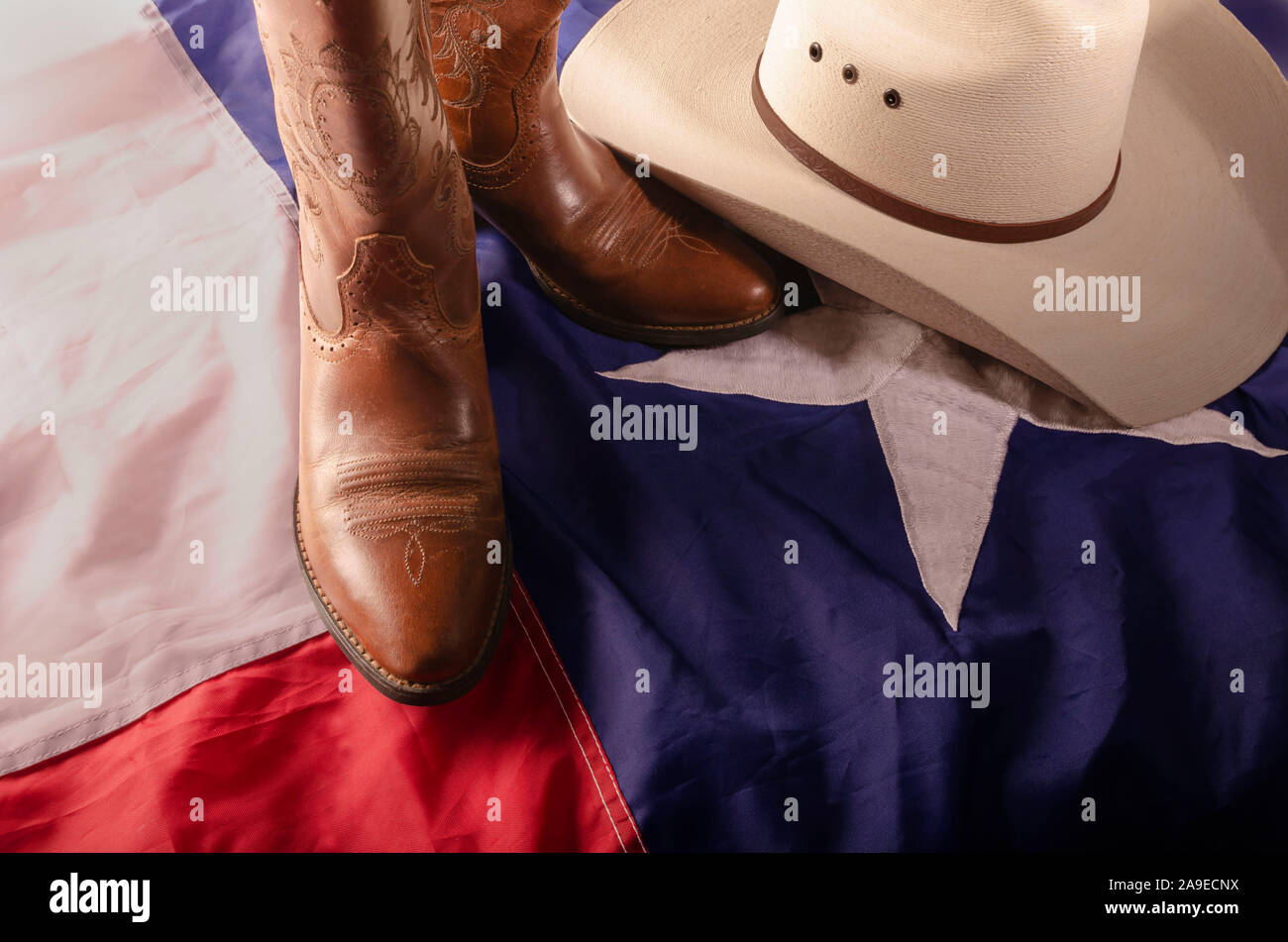 Cowboy hat and boots represent a way of life in the great state of Texas by resting on the Lone star state flag. Stock Photo