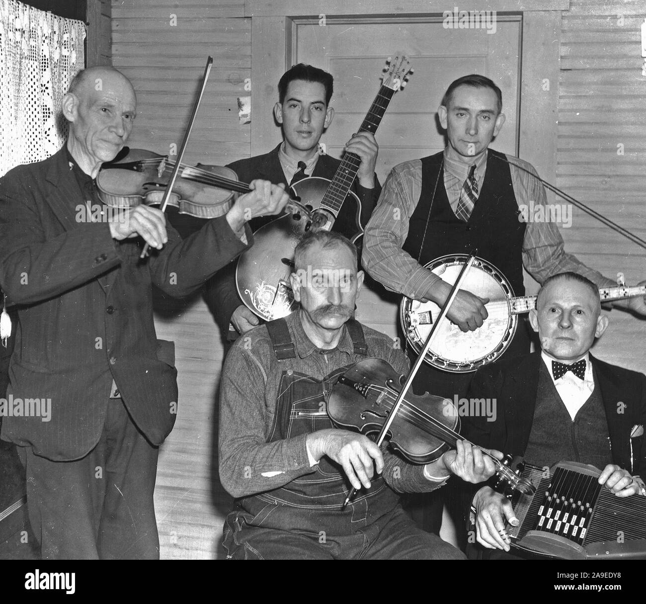 Members of the Bog Trotters Band, posed holding their instruments, Galax, Va. Back row: Uncle Alex Dunford, fiddle; Fields Ward, guitar; Wade Ward, banjo. Front row: Crockett Ward, fiddle; Doc Davis, autoharp Stock Photo
