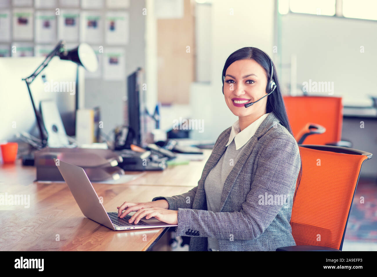 Beautiful call center agent browsing the internet on her computer Stock Photo