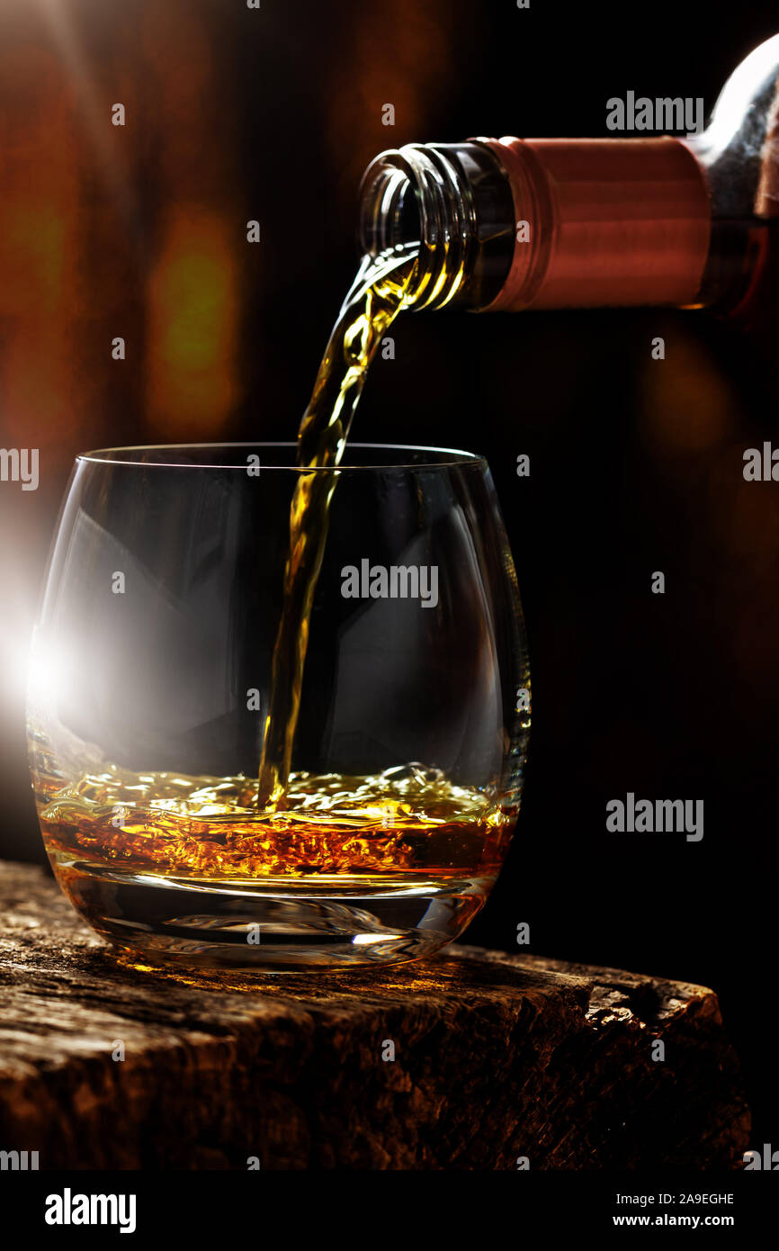 Whisky is poured from the bottle into a whisky glass Stock Photo