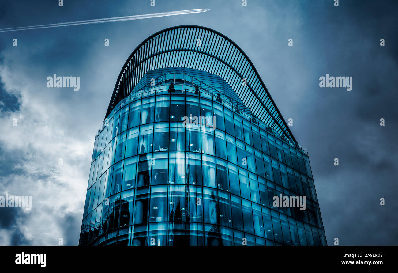 Modern glass building with airplane in the sky Stock Photo