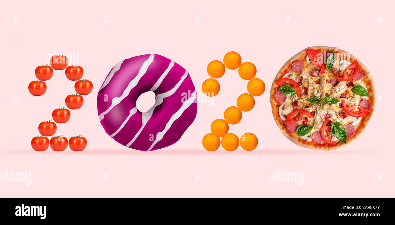 2020 made from unhealthy food on coral background. Pink glazed donut and pizza's slices, tomatos and oranges. Copyspace, nutrition and delicious eating. New Year's and Merry Christmas concept. Stock Photo