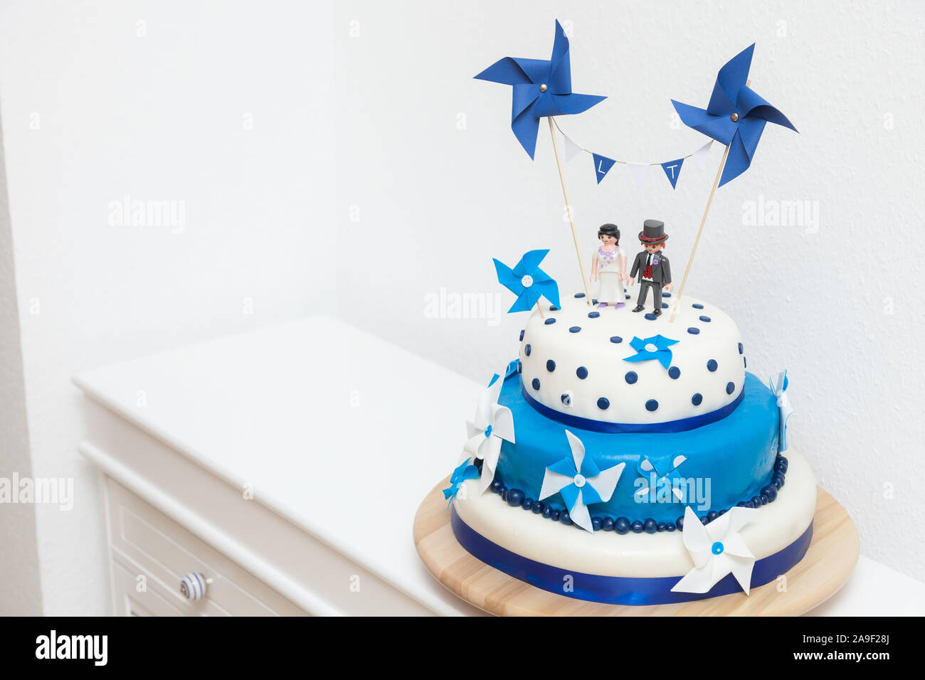 Beautiful white and blue wedding cake decorated with paper wind mills and  playmobil figures Stock Photo - Alamy