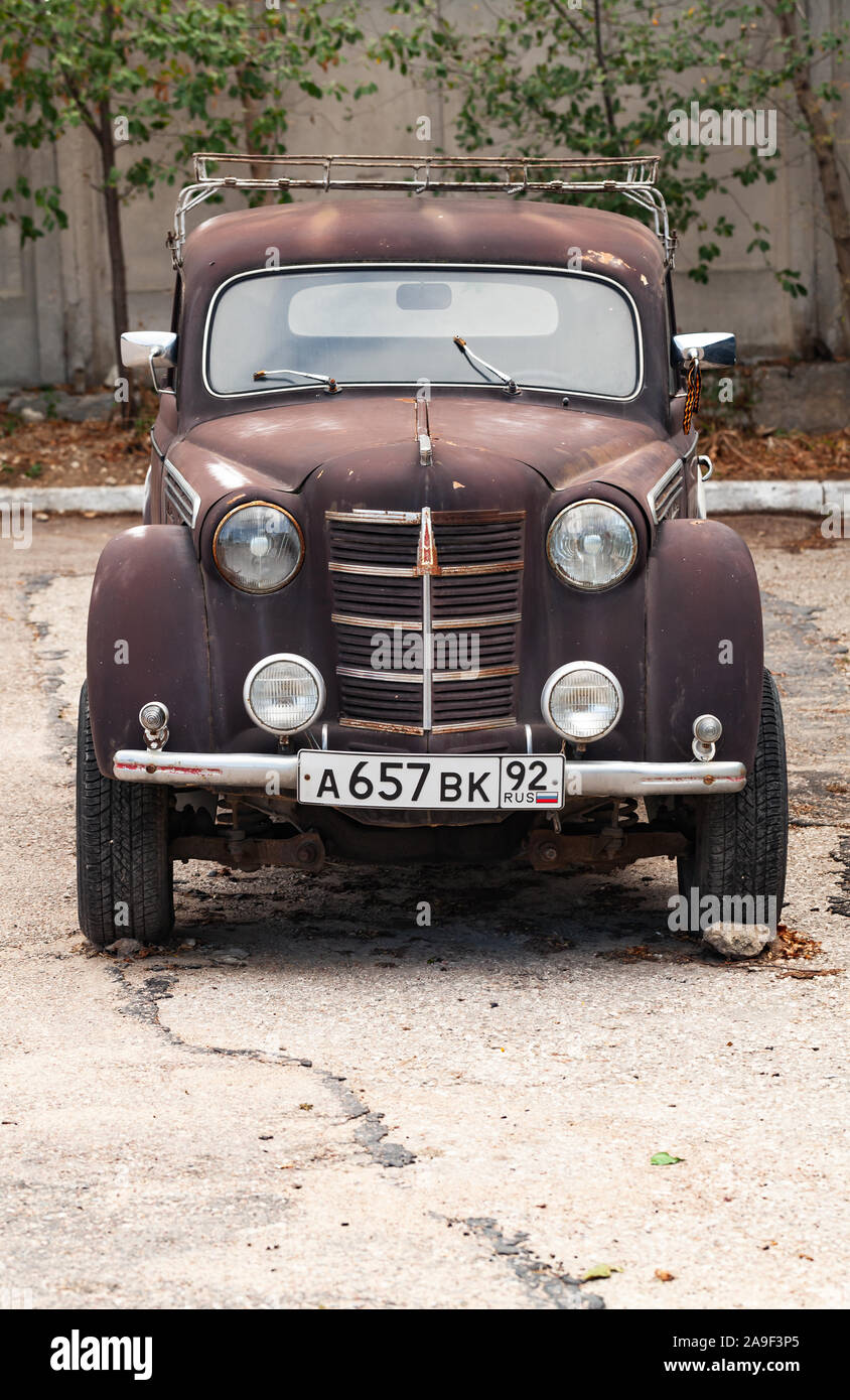 Sevastopol, Crimea - September 22, 2019: Old timer Moskvitch 400, Soviet compact car stands on an empty parking lot, vertical photo, front view Stock Photo