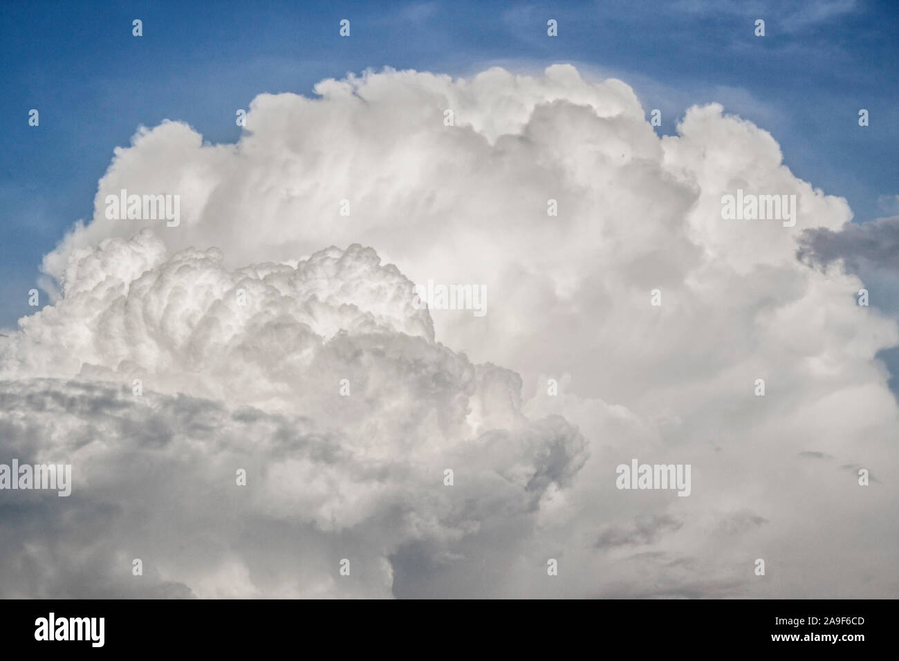 A cumulus cloud floats across the sky like a big mountain. A thunderous front is approaching. Beautiful heavenly phenomenon. Aerial landscape. Stock Photo