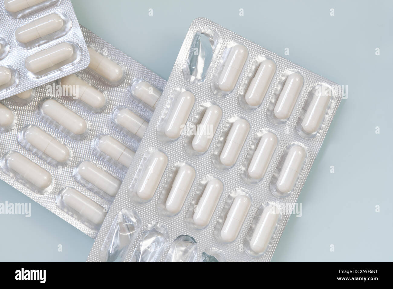 White capsules in silver packaging filled with the nutritional supplements of zinc and selenium are lying unopened on a white background. Stock Photo