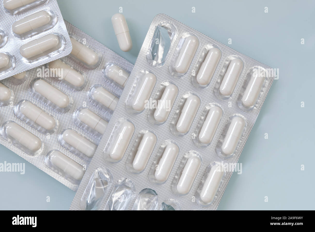 White capsules in silver packaging filled with the nutritional supplements of zinc and selenium are lying unopened on a white background. Stock Photo